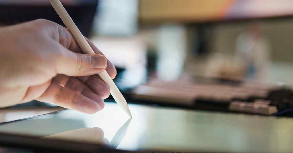 Professional reviewing AI-generated resume content on digital tablet with laptop in background showing AI resume builder interface and job application materials