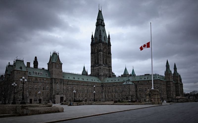 View of Canada’s Parliament Buildings in Ottawa under an overcast sky, reflecting public sector layoffs and workforce reductions