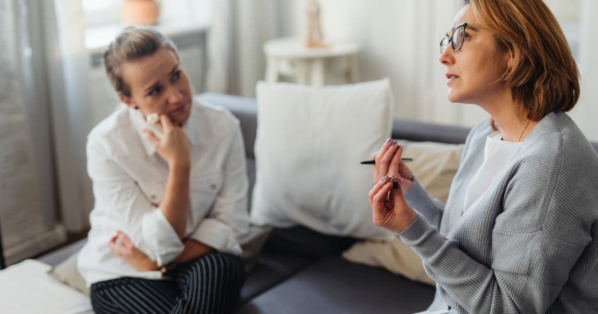 A job seeker and career coach sitting across from each other at a desk, reviewing documents and discussing career strategy in a professional setting