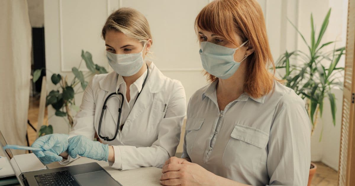 Registered nurse reviewing a nursing resume on a laptop with a patient, illustrating Canadian nursing hiring and ATS screening